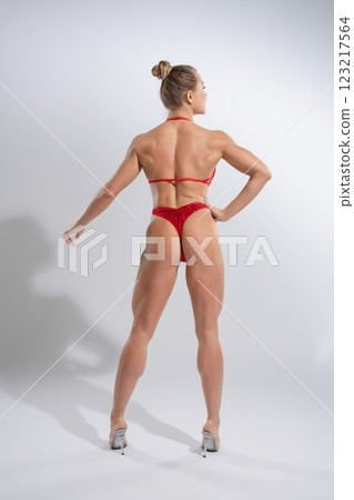 Woman showcasing fitness and strength in red lingerie against a plain backdrop Woman showcasing fitness and strength in red lingerie against a plain backdrop 123217564