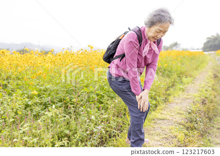 Senior woman suffering with knee pain while hiking on the  park 123217603