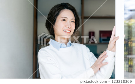 Woman opening the living room window 123218369