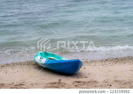 A blue and green kayak on a tropical sandy beach with the emerald green sea in the background 123219562