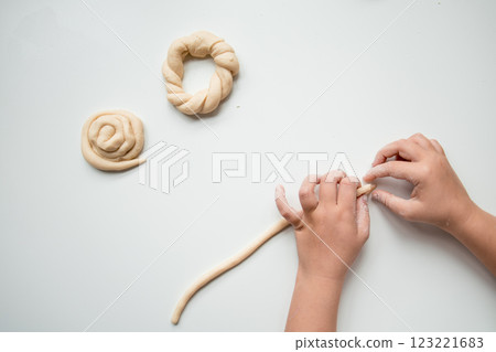 Child forming dough into shapes on white surface 123221683