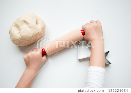 Child rolling dough with wooden pin and star shaped cookie cutter Child rolling dough with wooden pin and star shaped cookie cutter 123221684