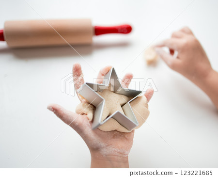 Child making star shaped cookies with dough and cutter in kitchen Child making star shaped cookies with dough and cutter in kitchen 123221685