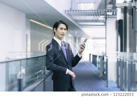 A young businessman wearing a suit and operating a smartphone. Photo courtesy of Sky Perfect Tokyo Media Center. 123222053