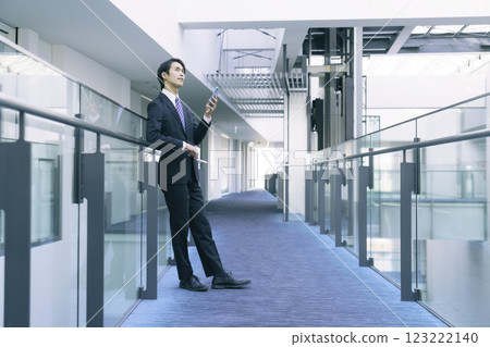 一位身穿西裝、操作智慧型手機的年輕商人。 一位身穿西裝、操作智慧型手機的年輕商人。 123222140