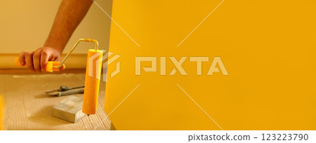 A close-up of a paint roller applying fresh yellow paint to a wall, creating a smooth and vibrant finish. The image highlights the process of home improvement, interior design, and renovation A close-up of a paint roller applying fresh yellow paint to a wall, creating a smooth and vibrant finish. The image highlights the process of home improvement, interior design, and renovation 123223790