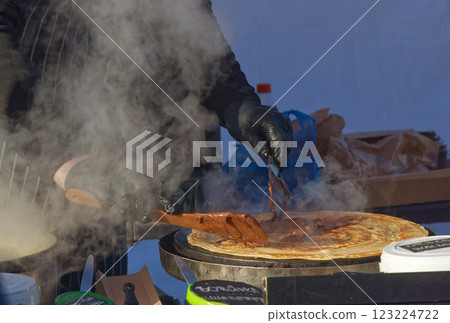 Close-Up of Hands Preparing Chocolate Crepe on a Griddle with Steam Close-Up of Hands Preparing Chocolate Crepe on a Griddle with Steam 123224722