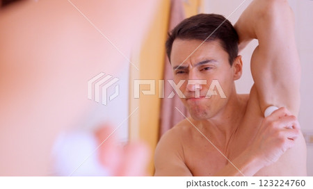 Man putting roll on deodorant on armpit in bathroom 123224760