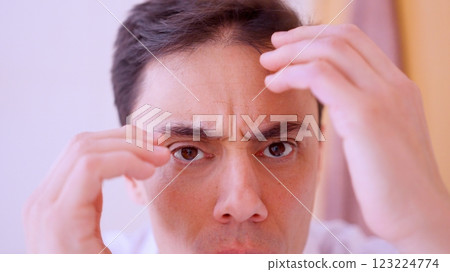 Worried man checking hair loss and touching forehead Worried man checking hair loss and touching forehead 123224774