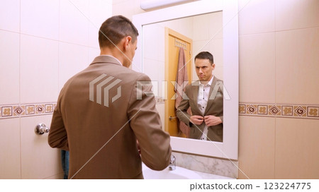 Businessman buttoning his jacket in the bathroom mirror Businessman buttoning his jacket in the bathroom mirror 123224775