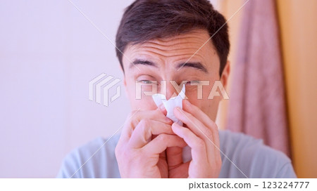 Sick man blowing nose with tissue at home Sick man blowing nose with tissue at home 123224777