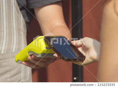 A woman holding smart phone and paying for goods. 123225035