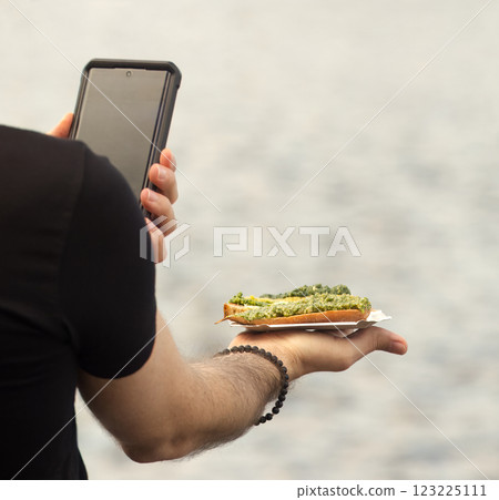 A man taking picture of his food at outdoor market 123225111