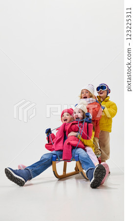 Group of children, girls and boys, dressed in colorful winter clothes sitting on sled, laughing, expressions full of happiness and excitement Group of children, girls and boys, dressed in colorful winter clothes sitting on sled, laughing, expressions full of happiness and excitement 123225311