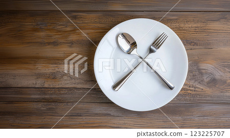 Fasting concept with spoon and fork crossed on simple plate	 123225707