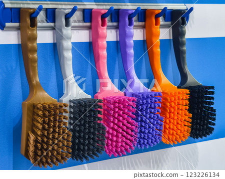 Variety of colorful cleaning brushes displayed on a wall in an organized manner for easy access and selection 123226134
