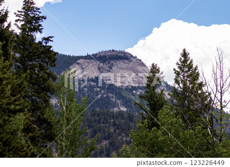 Rocky Mountain Peak Surrounded by Lush Green Trees on a Clear Day Rocky Mountain Peak Surrounded by Lush Green Trees on a Clear Day 123226449