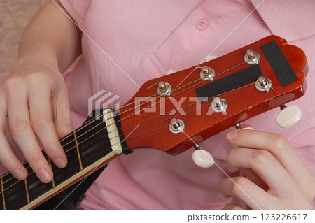 Extreme close-up woman's fingers tuning acoustic guitar. Daily routine process Extreme close-up woman's fingers tuning acoustic guitar. Daily routine process 123226617