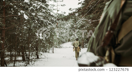 Usa Army Soldiers Of World War Ii. Heroes Of War. Re-enactors Dressed As American Infantry Soldier Marching Through Forest Road In Cold Winter Day. Group Of Usa Soldiers Marching Country Road Usa Army Soldiers Of World War Ii. Heroes Of War. Re-enactors Dressed As American Infantry Soldier Marching Through Forest Road In Cold Winter Day. Group Of Usa Soldiers Marching Country Road 123227676