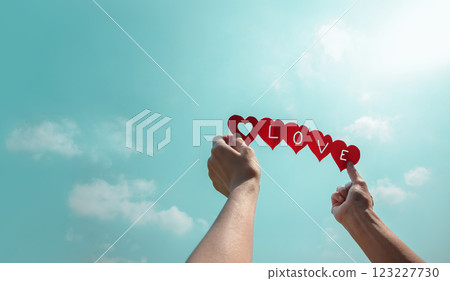 Love, Community and Unity Concepts. Social Cooperation. Organization or Charity. Hand Raise up a Paper Cut of many Hearts into the Sky. Spread Love Together 123227730