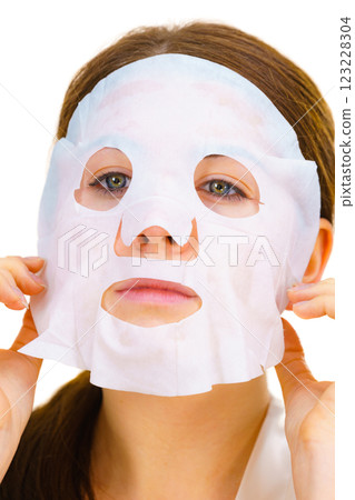 Woman applying sheet mask on face 123228304