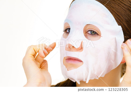 Woman applying sheet mask on face Woman applying sheet mask on face 123228305