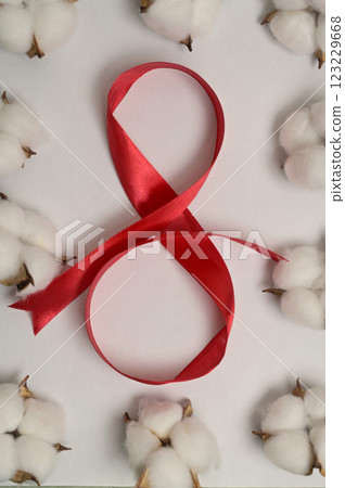 International Women's Day 8 March. Red silk ribbon on white background. Cotton inflorescence plant. Greeting card 123229668