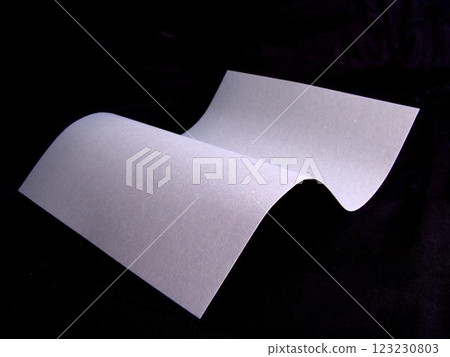 Wavy paper sheet over black background Wavy paper sheet over black background 123230803