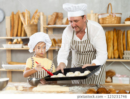 Daughter helps father baker to make pastries, lubricate croissants with loosened egg 123231746