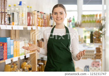 Young woman seller in apron stands in trading hall of store 123231747