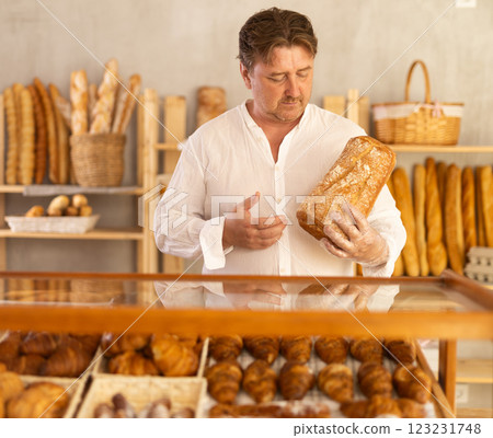 Portrait of happy male customer holding bread in his hands in private bakery 123231748