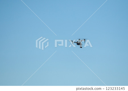 Drone flying with a camera against blue sky 123233145