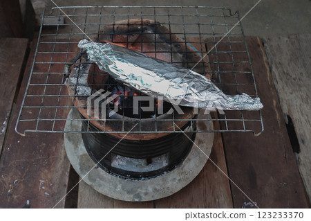 Grilled fish in aluminum foil on Charcoal stove cooking concept. 123233370