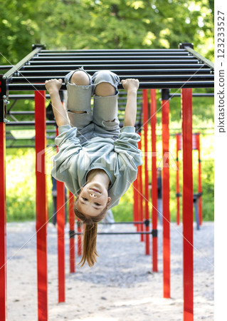 Young girl hanging upside down on a jungle gym in outdoor park Young girl hanging upside down on a jungle gym in outdoor park 123233527