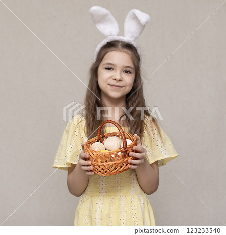 Smiling girl in bunny ears holding Easter basket with decorated eggs 123233540