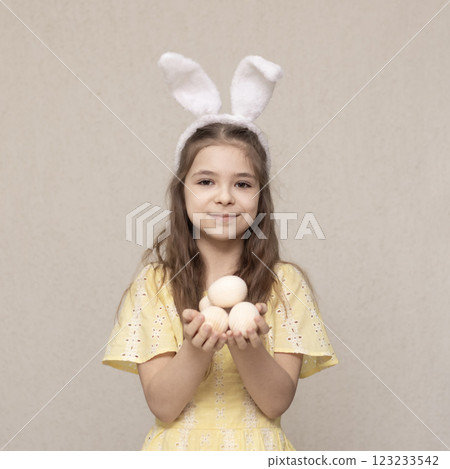 Young girl holding decorative eggs wearing bunny ears for Easter celebration 123233542