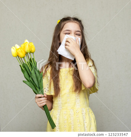 Little girl in yellow sneezing holding flowers due to seasonal allergies Little girl in yellow sneezing holding flowers due to seasonal allergies 123233547