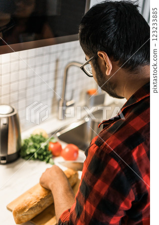 Close-up Indian or latino man cooking breakfast while standing at the kitchen at home, rear view Close-up Indian or latino man cooking breakfast while standing at the kitchen at home, rear view 123233885