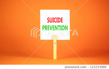 Suicide prevention symbol. Concept words Suicide prevention on beautiful white paper on clothespin. Beautiful orange table orange background. Psychological and suicide prevention concept. Copy space. 123233900