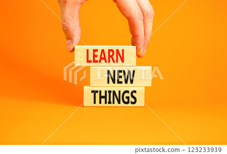 Learn new things symbol. Concept words Learn new things on beautiful wooden blocks. Beautiful orange background. Businessman hand. Business motivational learn new things concept. Copy space. 123233939