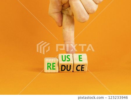 Reuse or reduce symbol. Concept words Reuse Reduce on wooden block. Beautiful orange table orange background. Businessman hand. Business reuse or reduce concept. Copy space. 123233946