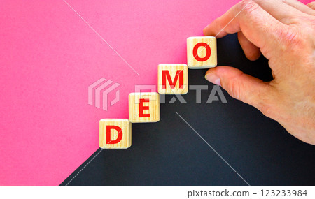 Demo symbol. Concept word Demo on beautiful wooden blocks. Businessman hand. Beautiful black and purple background. Business and demo concept. Copy space. 123233984