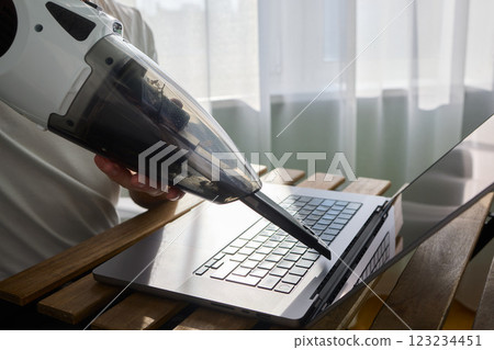 Using a handheld vacuum cleaner is an effective method for diligently cleaning a laptop 123234451