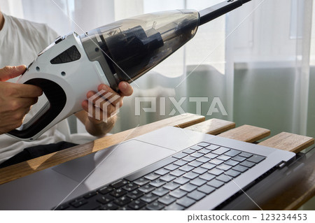 Using a handheld vacuum cleaner is an effective method for diligently cleaning a laptop 123234453