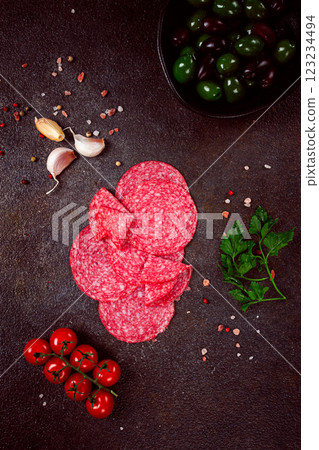 composition of sliced salami, with fresh tomatoes, garlic and green olives, on a dark surface, appetizer, no people, 123234494