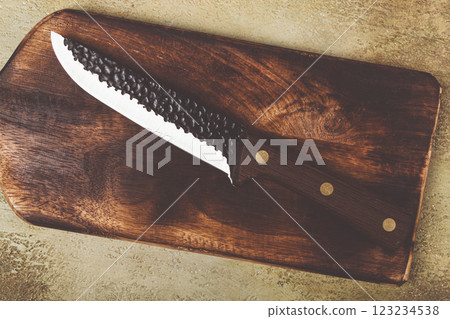 High-quality kitchen knife resting on a wooden cutting board with intricate textures and a rustic design High-quality kitchen knife resting on a wooden cutting board with intricate textures and a rustic design 123234538