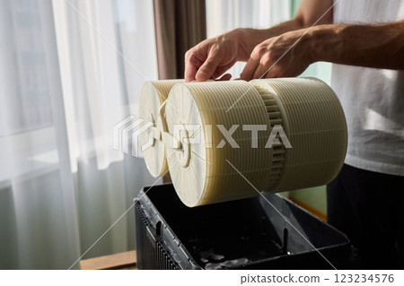 Hands are carefully handling industrial filters while inside a well-organized storage box 123234576