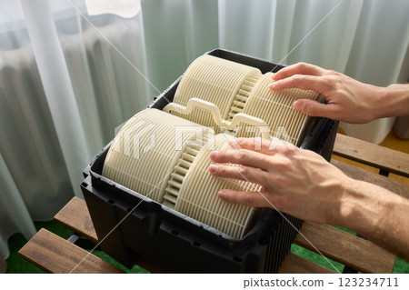 Hands are carefully handling industrial filters while inside a well-organized storage box 123234711