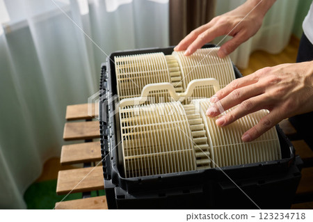 Hands are carefully handling industrial filters while inside a well-organized storage box 123234718
