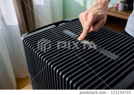 Hands adjusting a modern appliances control panel for optimal functionality and home comfort Hands adjusting a modern appliances control panel for optimal functionality and home comfort 123234735